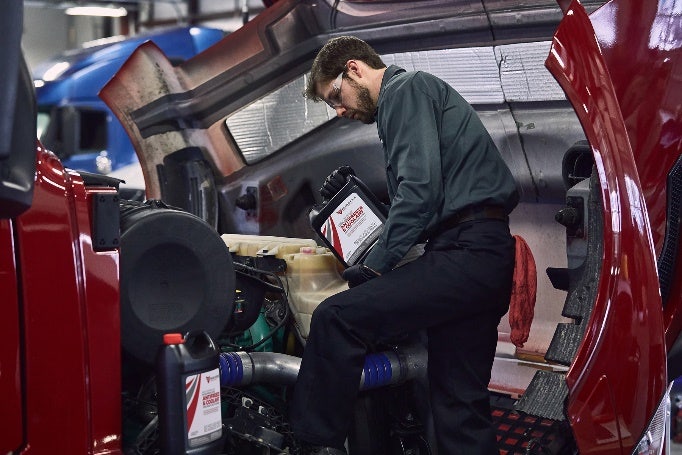 A person working on a car engine Description automatically generated